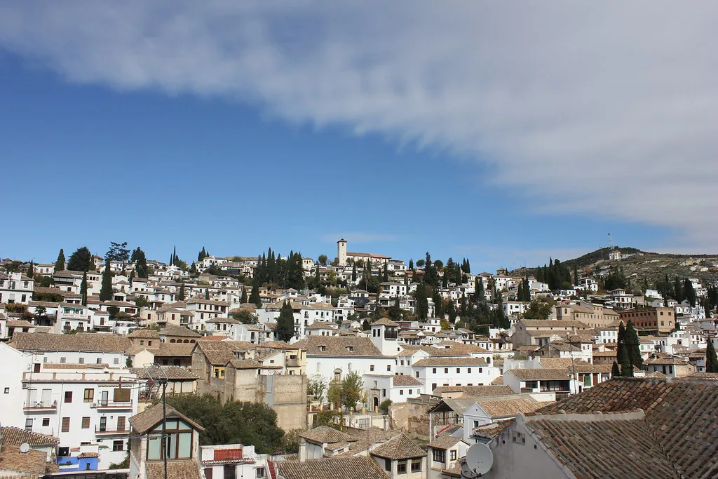 Sunlit cobblestoned street in Granada, Spain, ideal for breathable summer linen and sneakers