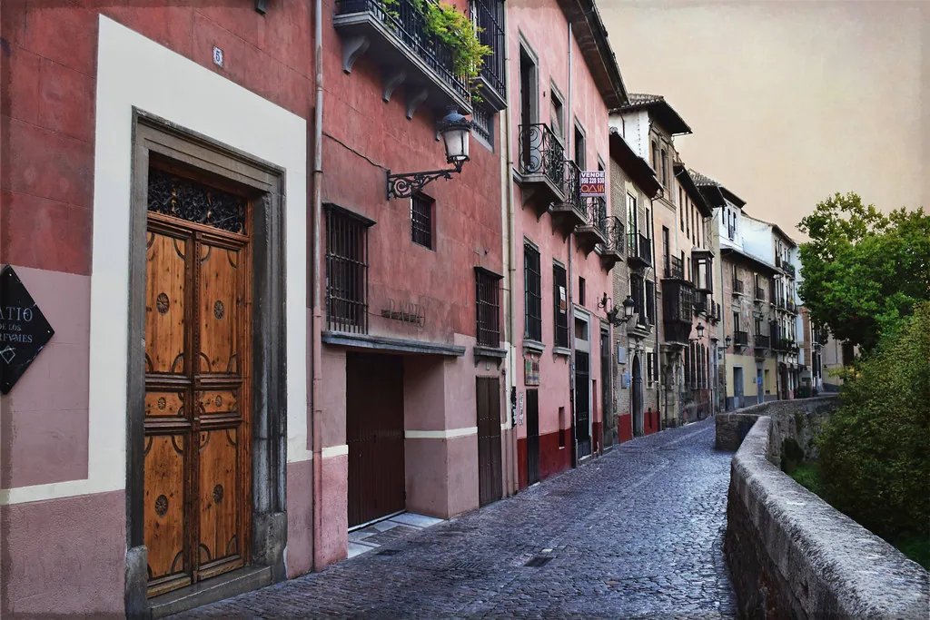 Sunlit cobblestone street in Granada, Spain in spring with whitewashed buildings