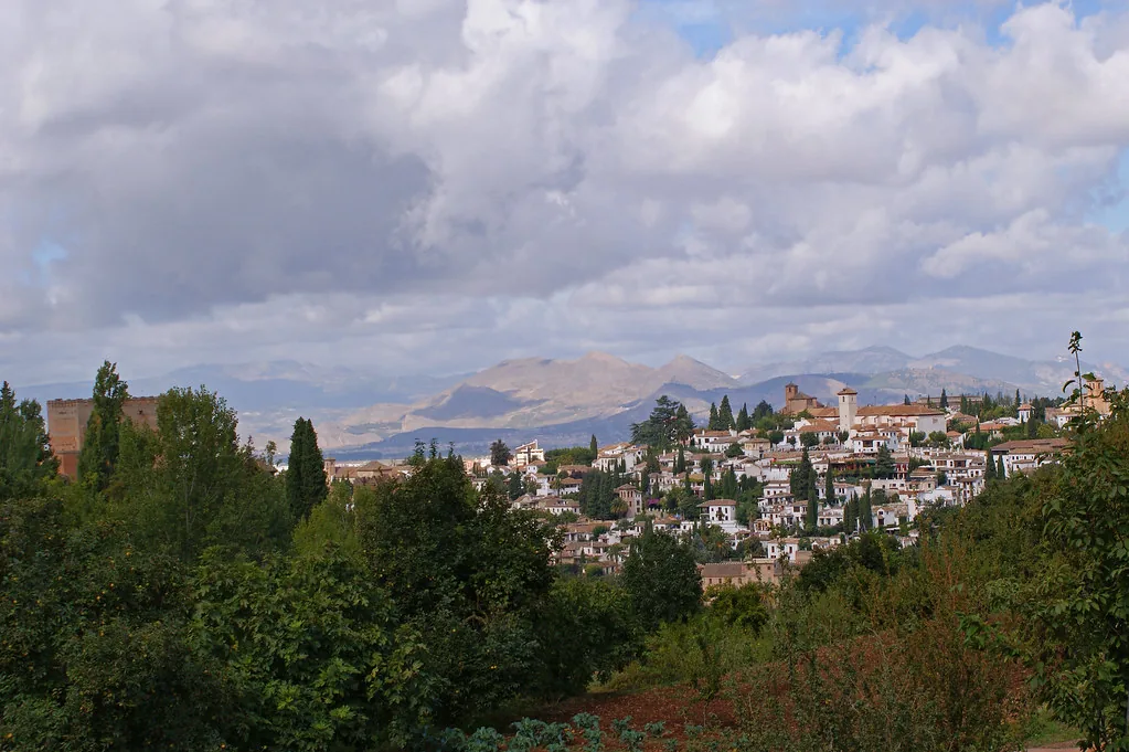 Sunlit Granada street with whitewashed buildings, ideal for light layered September outfits