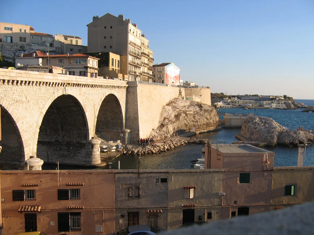 Sunlit Marseille street in winter showing limestone facades and pedestrians in coats