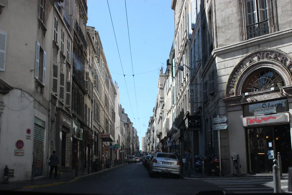 A sunlit street in Marseille, France, in early spring with locals in light jackets