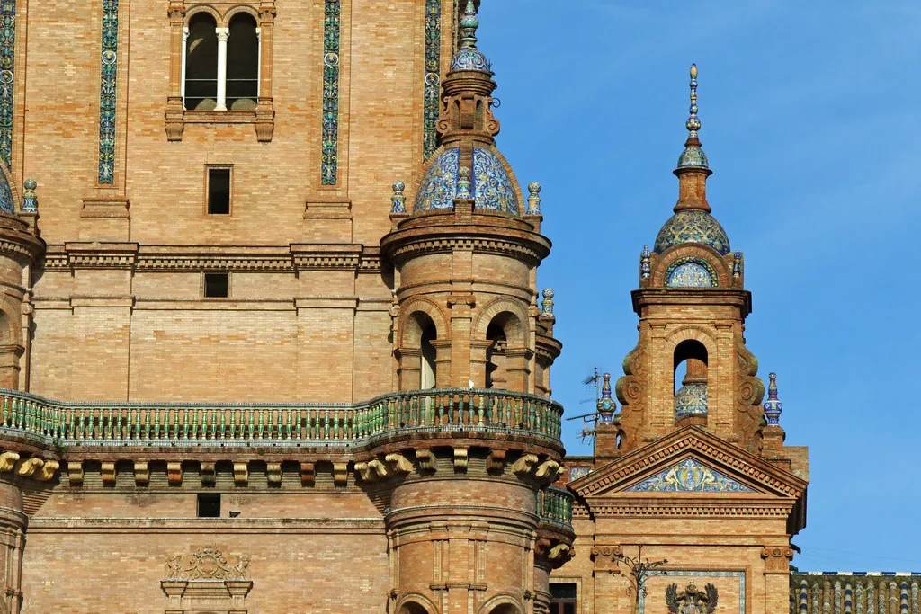 Sunlit cobblestone street in Seville's old town, lined with traditional Andalusian buildings