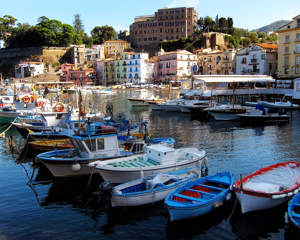 Sunlit street in Sorrento, Italy, lined with shops where summer travelers dress in light coastal clothing
